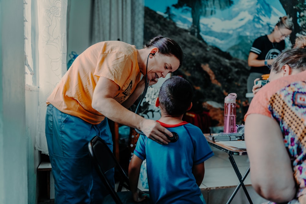 a man standing over a little boy who is sitting at a table