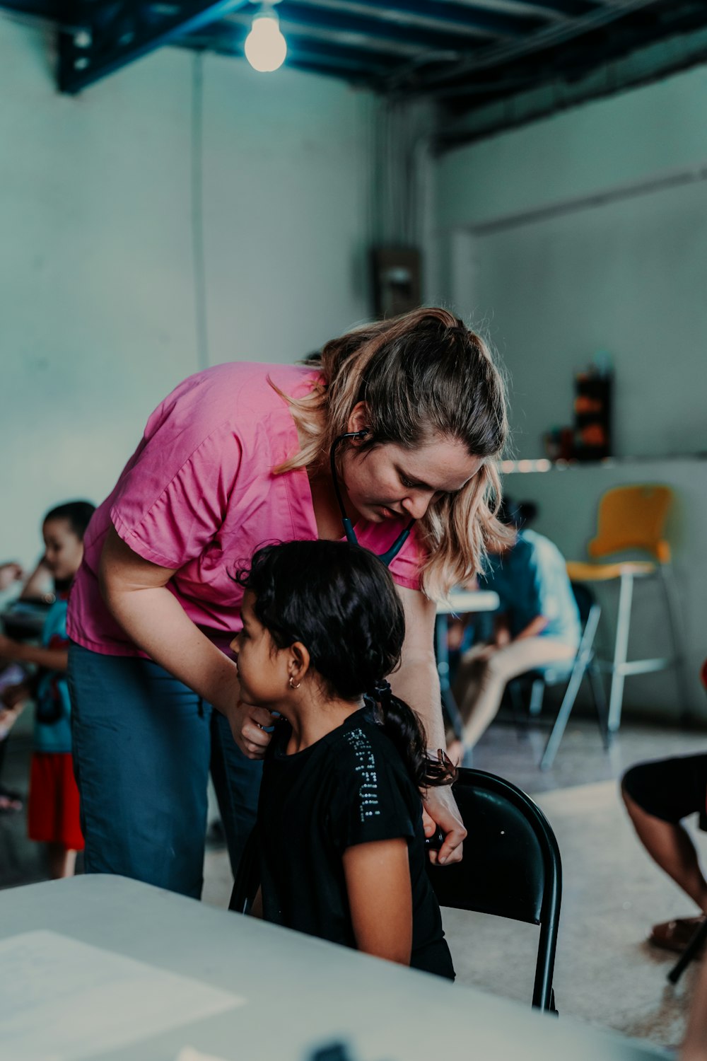 a woman helping a little girl with a chair