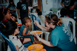 a woman feeding a plate of food to children