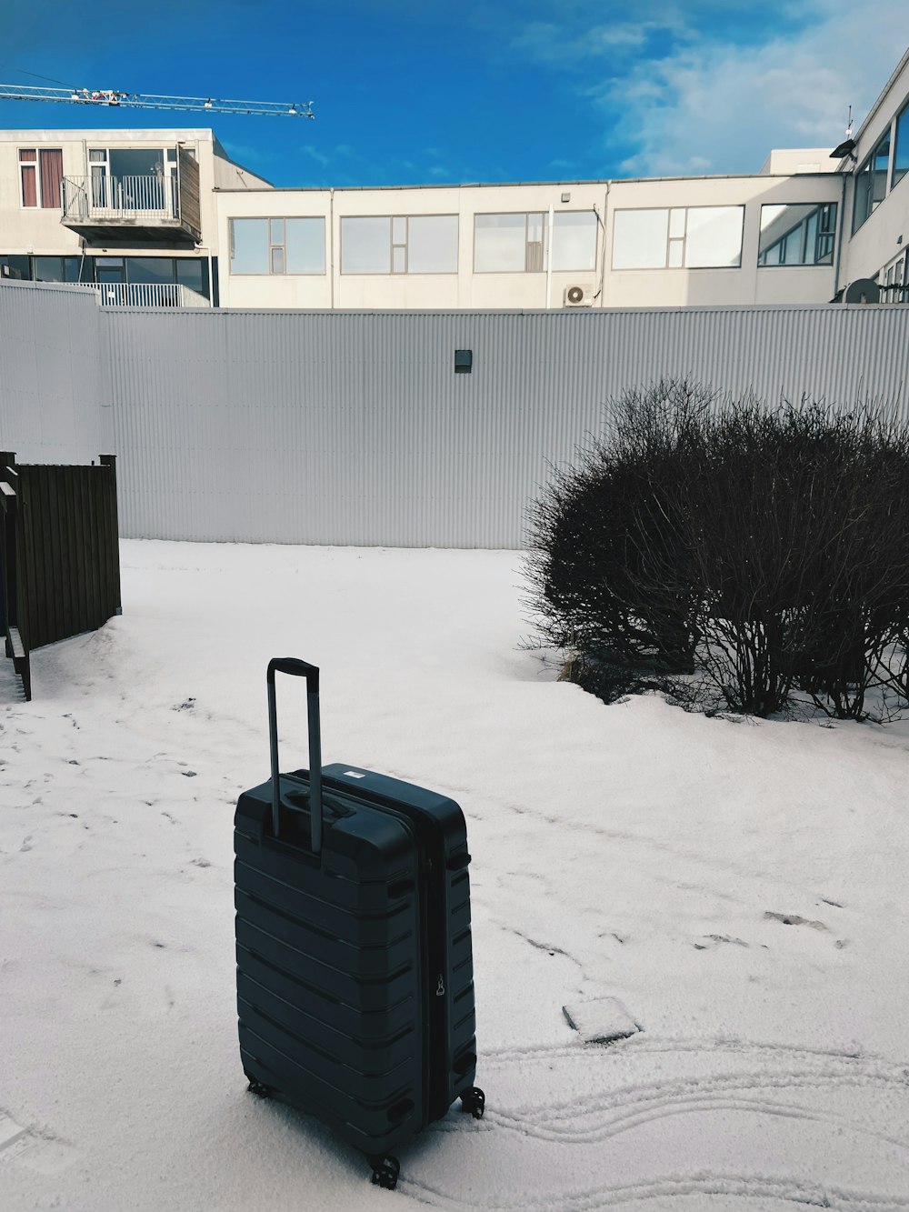 a suitcase sitting in the snow in front of a building