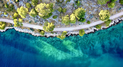 Aerial shot of a winding coastal path with turquoise waters below.