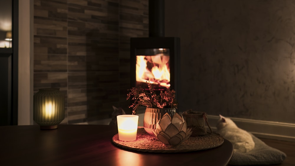 a lit candle sits on a table in front of a fireplace
