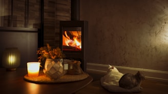 A softly glowing candle arrangement on a wooden table, surrounded by cozy blankets and a sleeping cat.