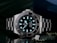 A luxury wristwatch with a luminous dial and markers, featuring a stainless steel bracelet and a rotating bezel. The watch face is adorned with the brand logo, offering a sleek and polished appearance against a dark background.