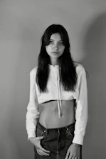 Model wearing a minimal white oversized t-shirt standing against a neutral urban backdrop.