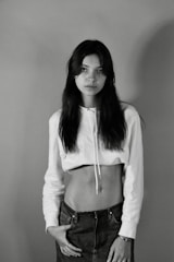 A model wearing a fitted white t-shirt with a minimalist logo, standing against a neutral backdrop.