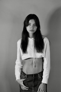 A model wearing a fitted white t-shirt with a minimalist logo, standing against a neutral backdrop.
