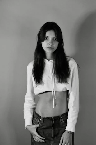 Model wearing a minimal white oversized t-shirt standing against a neutral urban backdrop.