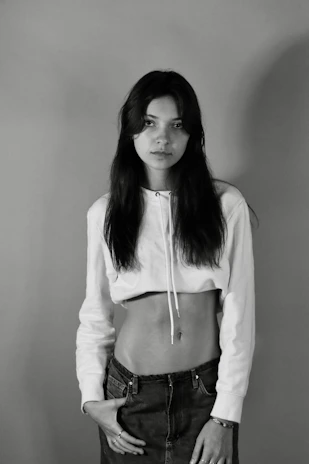 A model wearing a relaxed fit black oversized hoodie standing against a minimalist white wall.