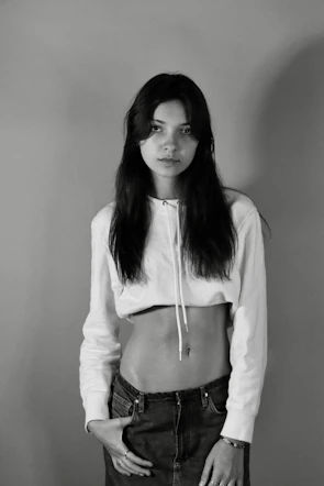 Model wearing a white hoodie with a minimalist red design, standing against a plain backdrop.