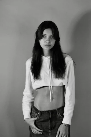 A minimalist black and white photo of a model wearing a plain oversized hoodie on a city street.