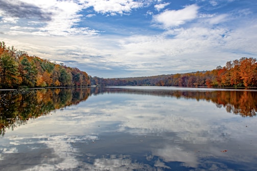 A serene lake reflecting autumn trees with vibrant colors.