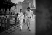 A smiling man and woman dressed elegantly, walking confidently in a city setting.