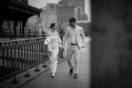 A smiling man and woman dressed elegantly, walking confidently in a city setting.