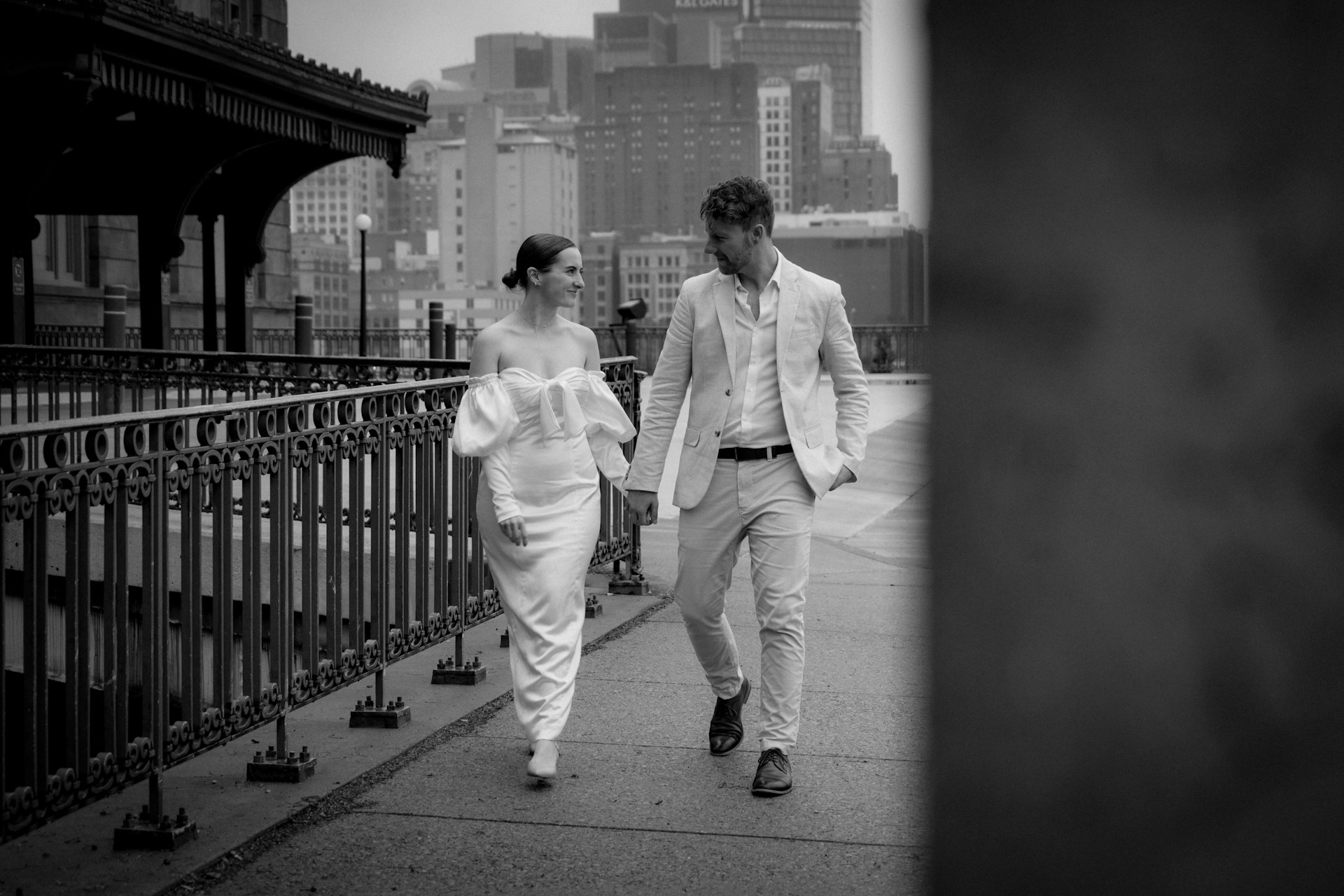 A stylish couple walking hand in hand through a vibrant city street, showcasing modern fashion.