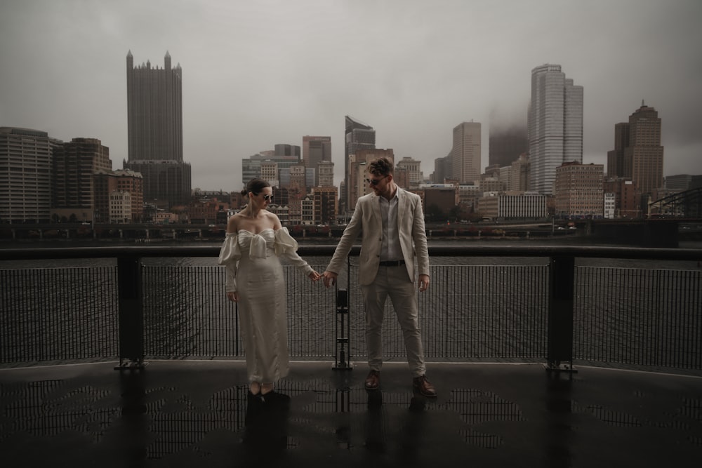 a man and a woman standing next to each other on a bridge
