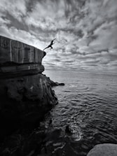 a person jumping off a cliff into the ocean
