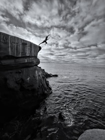a person jumping off a cliff into the ocean