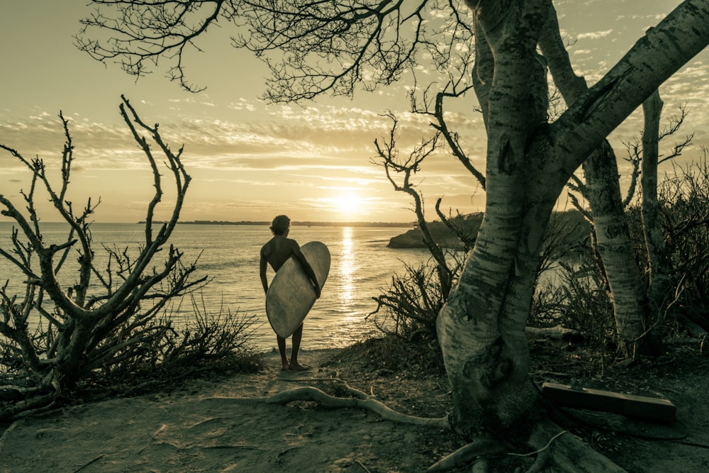 a man holding a surfboard walking towards the ocean