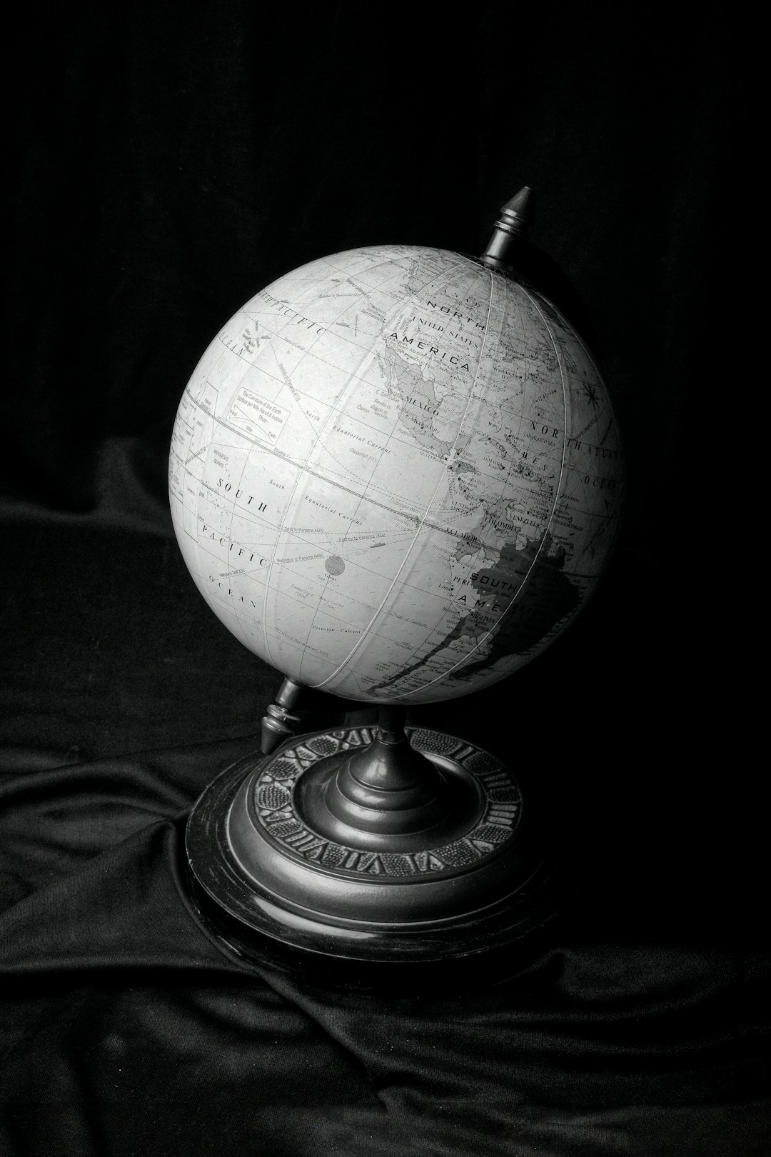 a black and white photo of a globe on a stand
