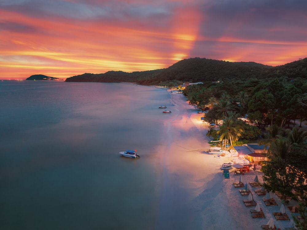 a beach at sunset with a boat in the water