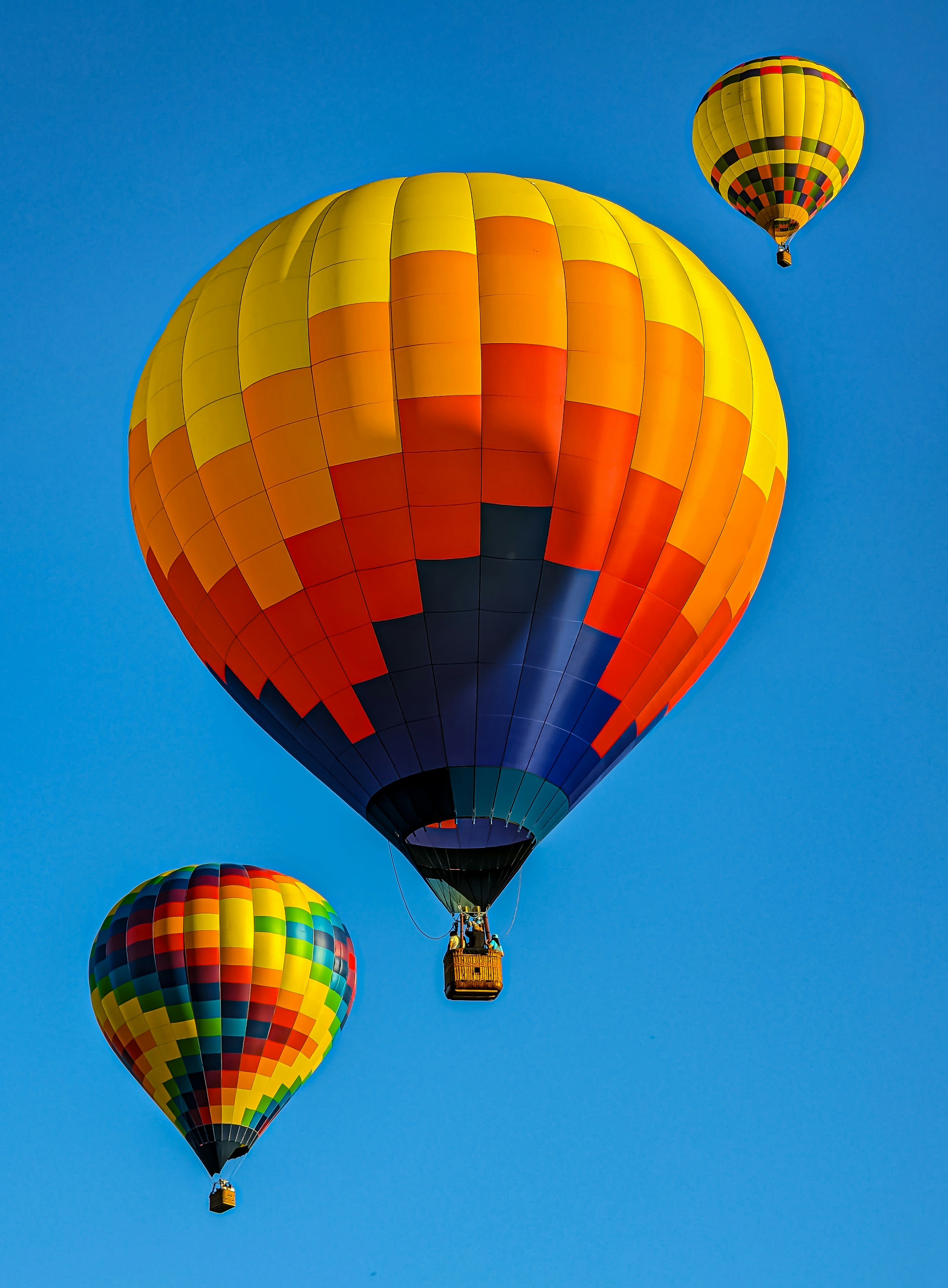 a group of hot air balloons flying through a blue sky