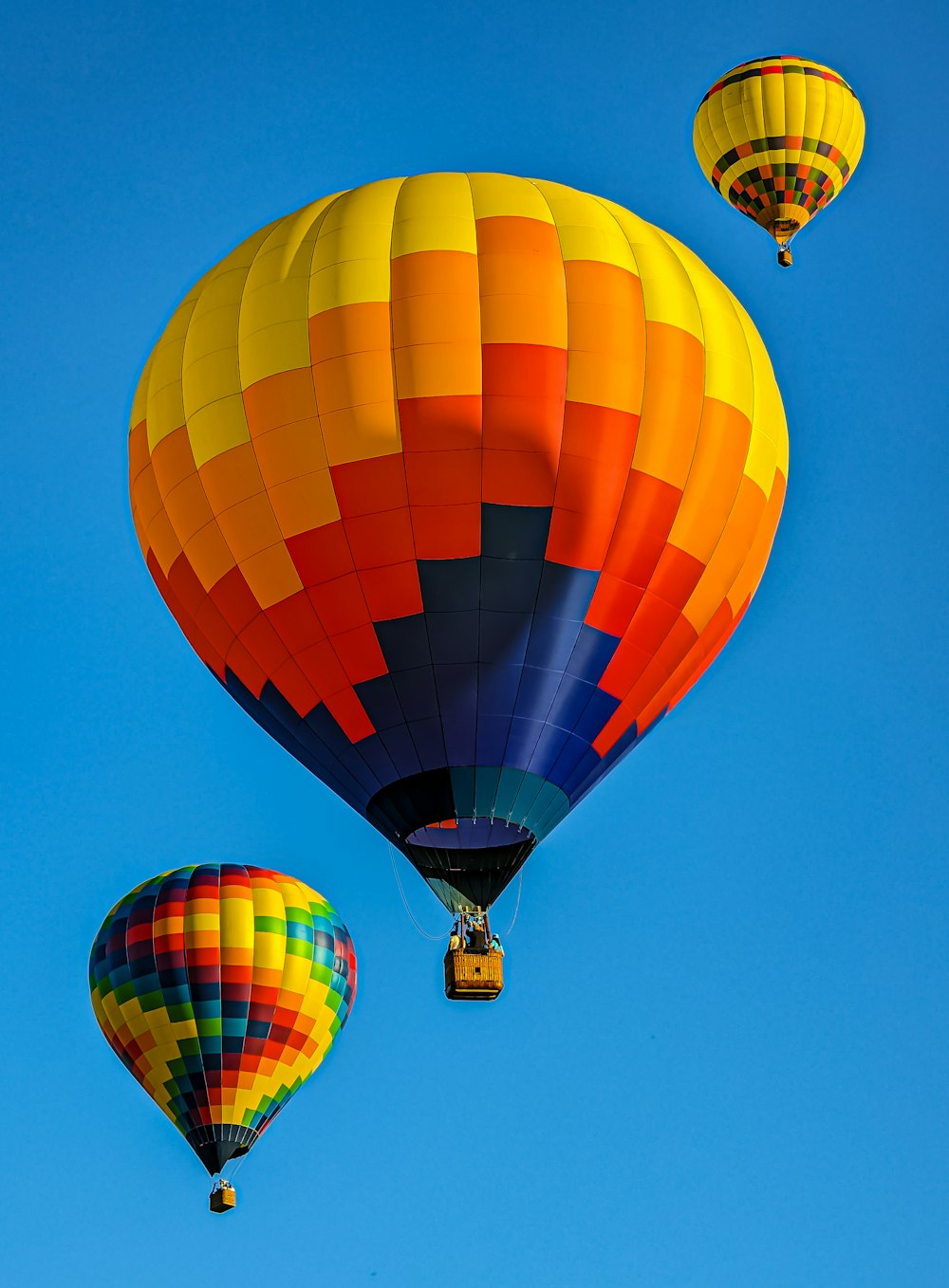 a group of hot air balloons flying through a blue sky