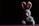 A plush blue bunny with pink inner ears and a pink nose is positioned against a dark background. The bunny is wearing a sheer ribbon tied around its neck and is sitting in a spotlight that highlights its fluffy texture, creating a strong contrast with the surrounding shadows.