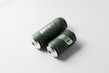Two green cans lie on a white surface, both featuring the word 'RIDGED' in a bold, metallic font. The design is minimalist, and the cans reflect light, suggesting a sleek and modern look.