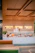 A cozy bakery counter with fresh bread, colorful sandwiches, and vibrant fruits displayed under soft green lighting.