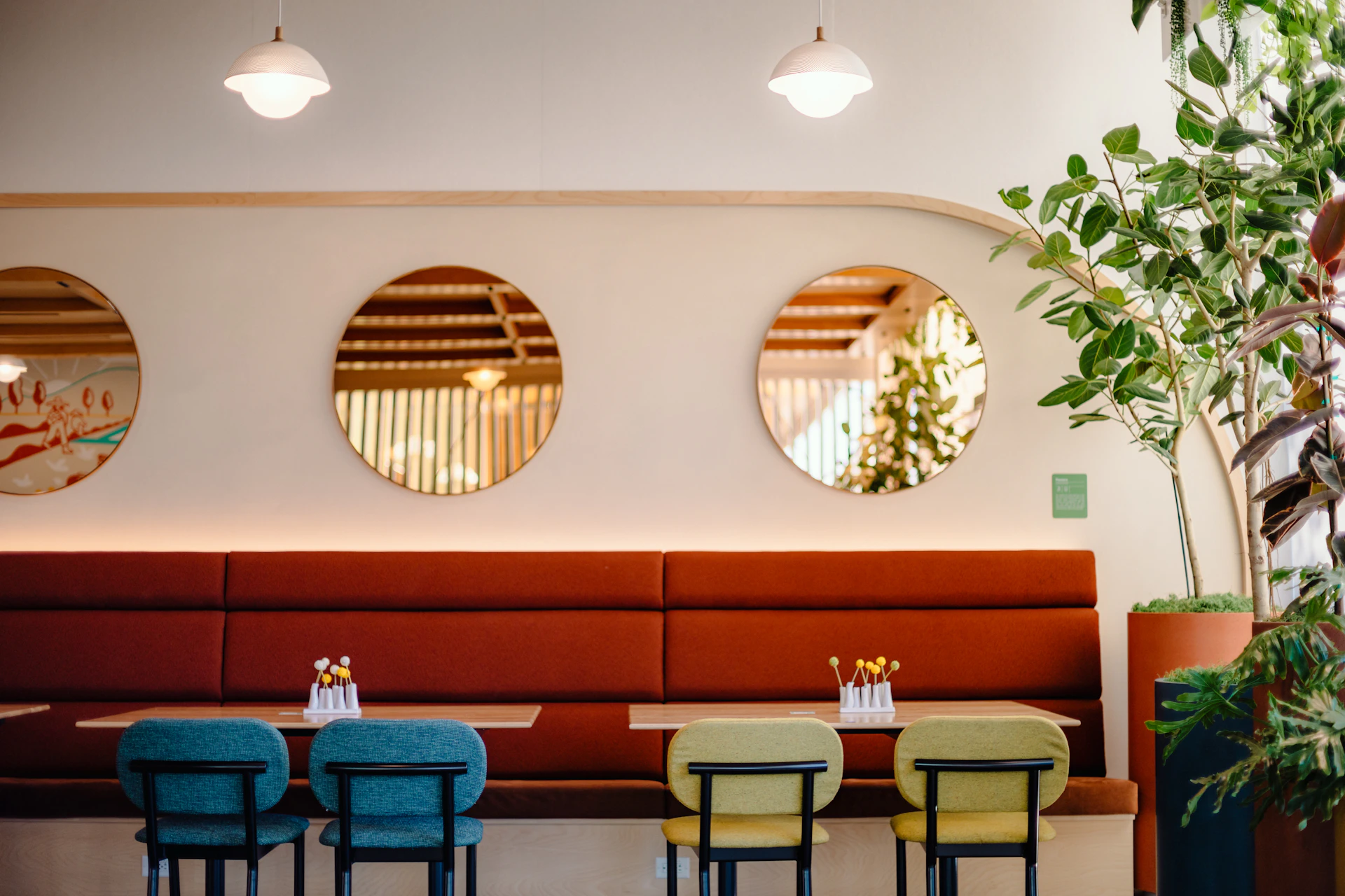 A stylish seating arrangement featuring contemporary wooden benches with green cushions, blending comfort with refined design in a trendy café setting.