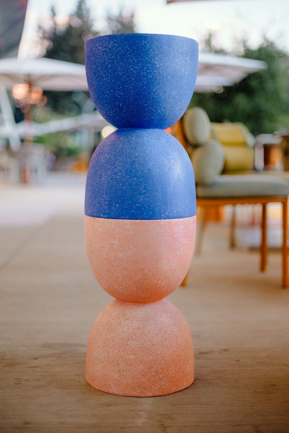 a blue and pink vase sitting on top of a wooden table