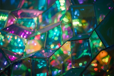 Vibrant and colorful reflections from mirrored glass surfaces create a kaleidoscope of light. Geometric patterns interlock in a mesmerizing display of hues.