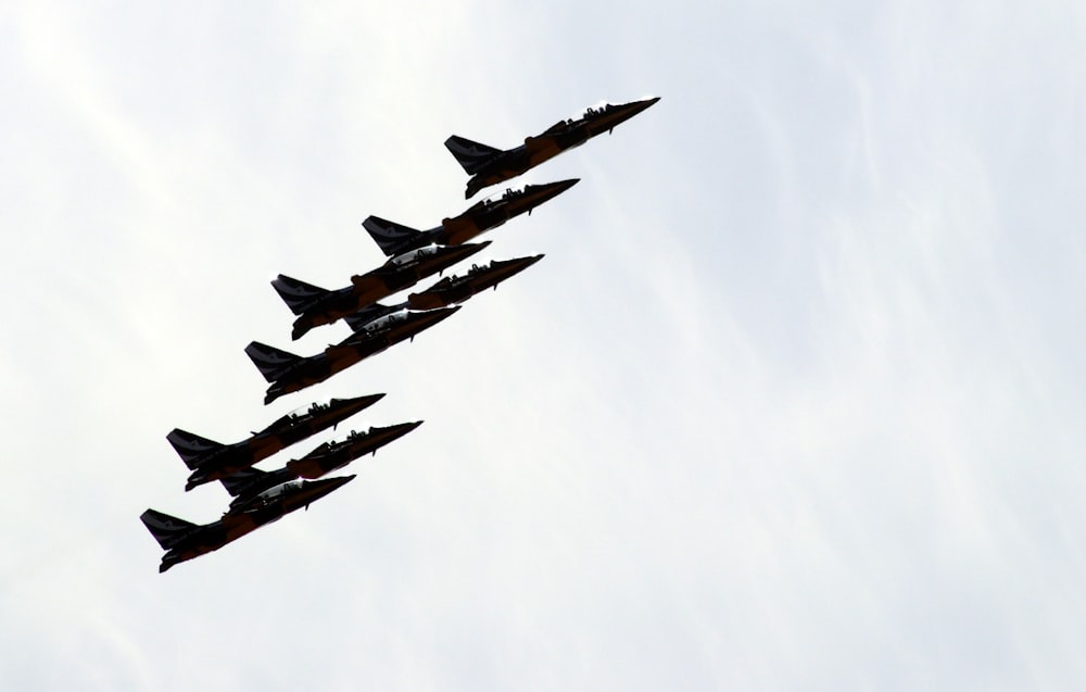 a formation of fighter jets flying through a cloudy sky