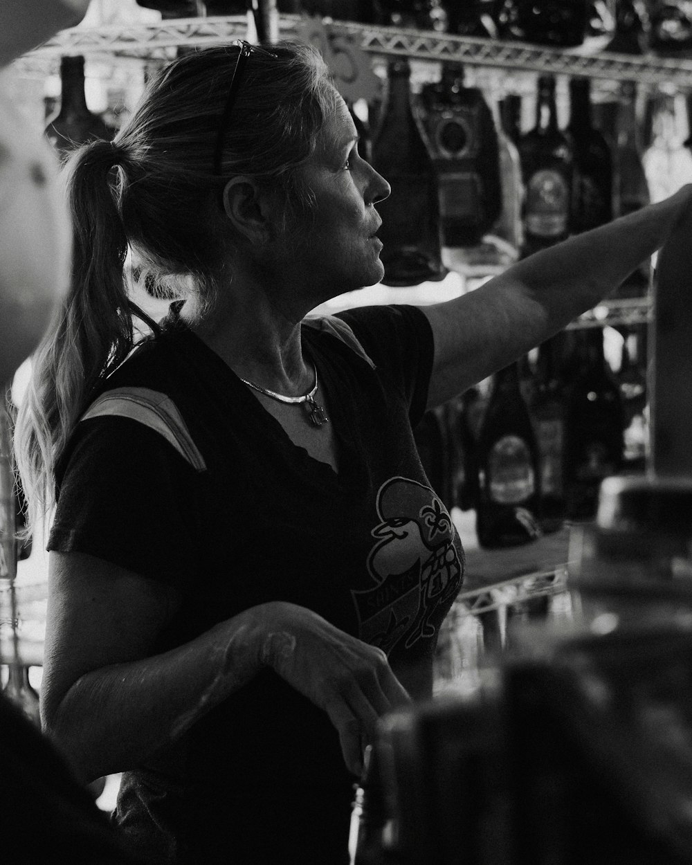 a woman standing in front of a bar filled with bottles