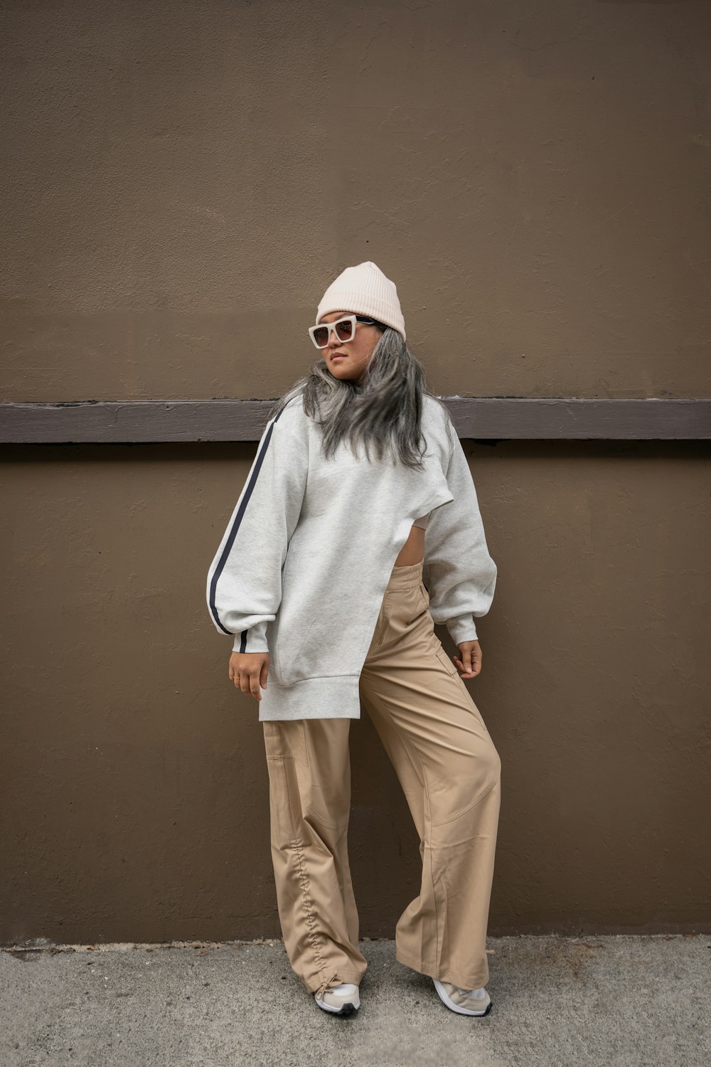 une femme aux cheveux gris vêtue d’un pull blanc et d’un pantalon kaki