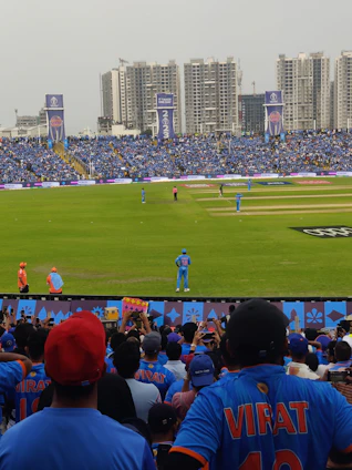 A lively scene of cricket fans cheering while placing bets on their phones during a thrilling match.