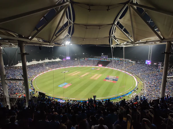 A vibrant stadium under floodlights with fans cheering during a thrilling cricket match.