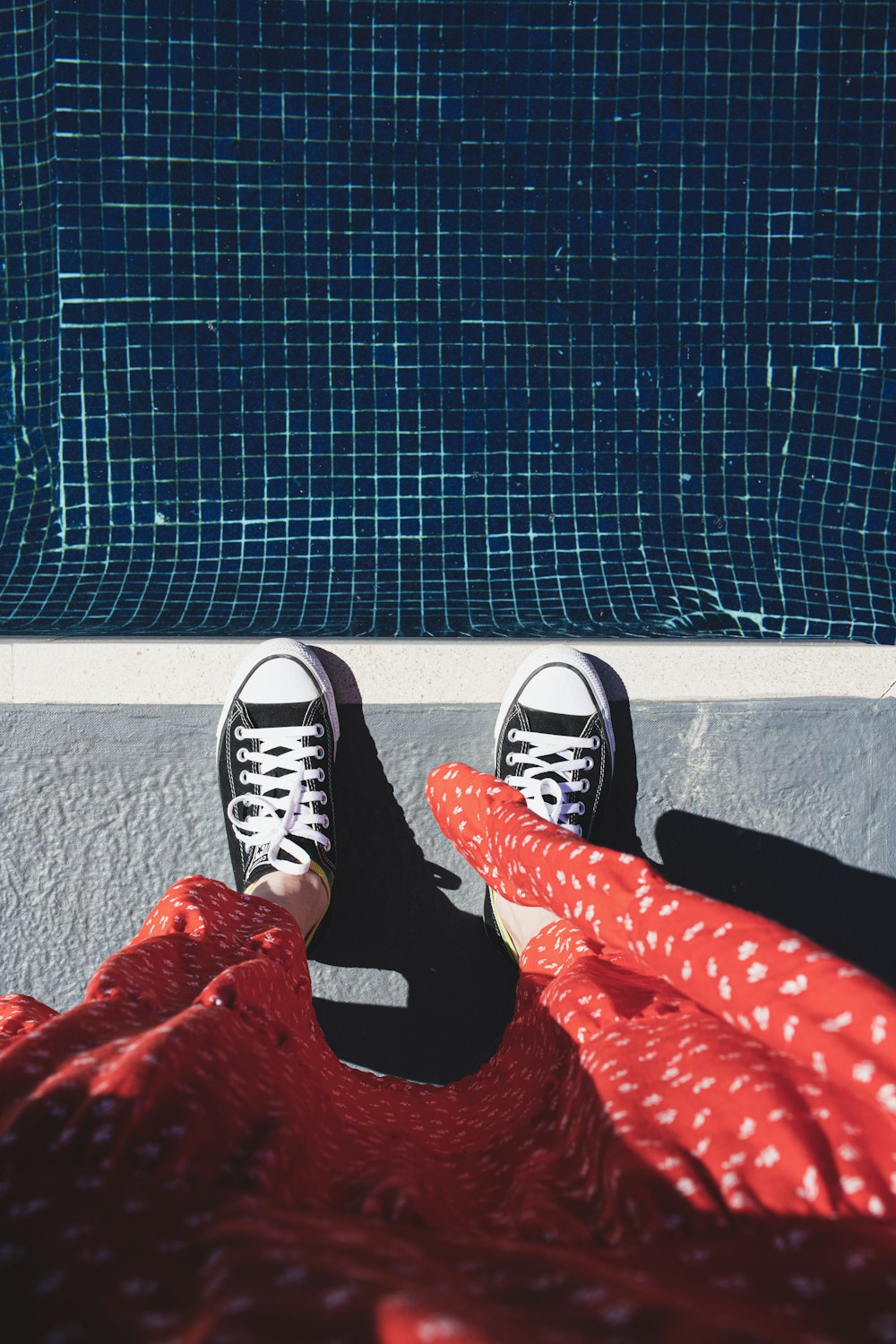 a person with their feet on a blanket near a swimming pool