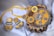 A set of intricately designed jewelry consisting of a necklace and matching earrings, with a vibrant yellow fabric backdrop. The pieces feature ornate silver floral patterns and decorative beads, presented elegantly on a wooden surface.