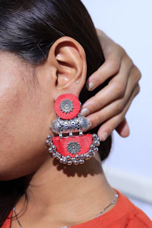 Close-up of a handcrafted polymer clay earring with ethnic patterns in soft pink tones