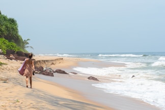 a woman walking on a beach with a surfboard