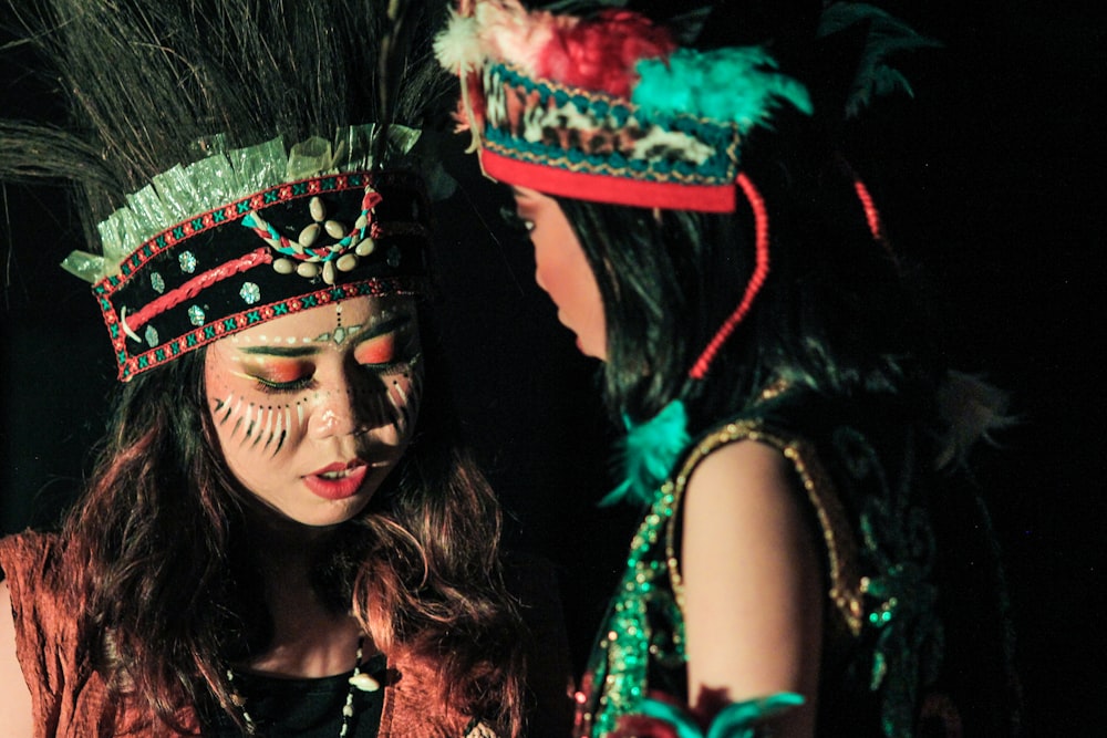 two women dressed in native american costumes looking at a cell phone