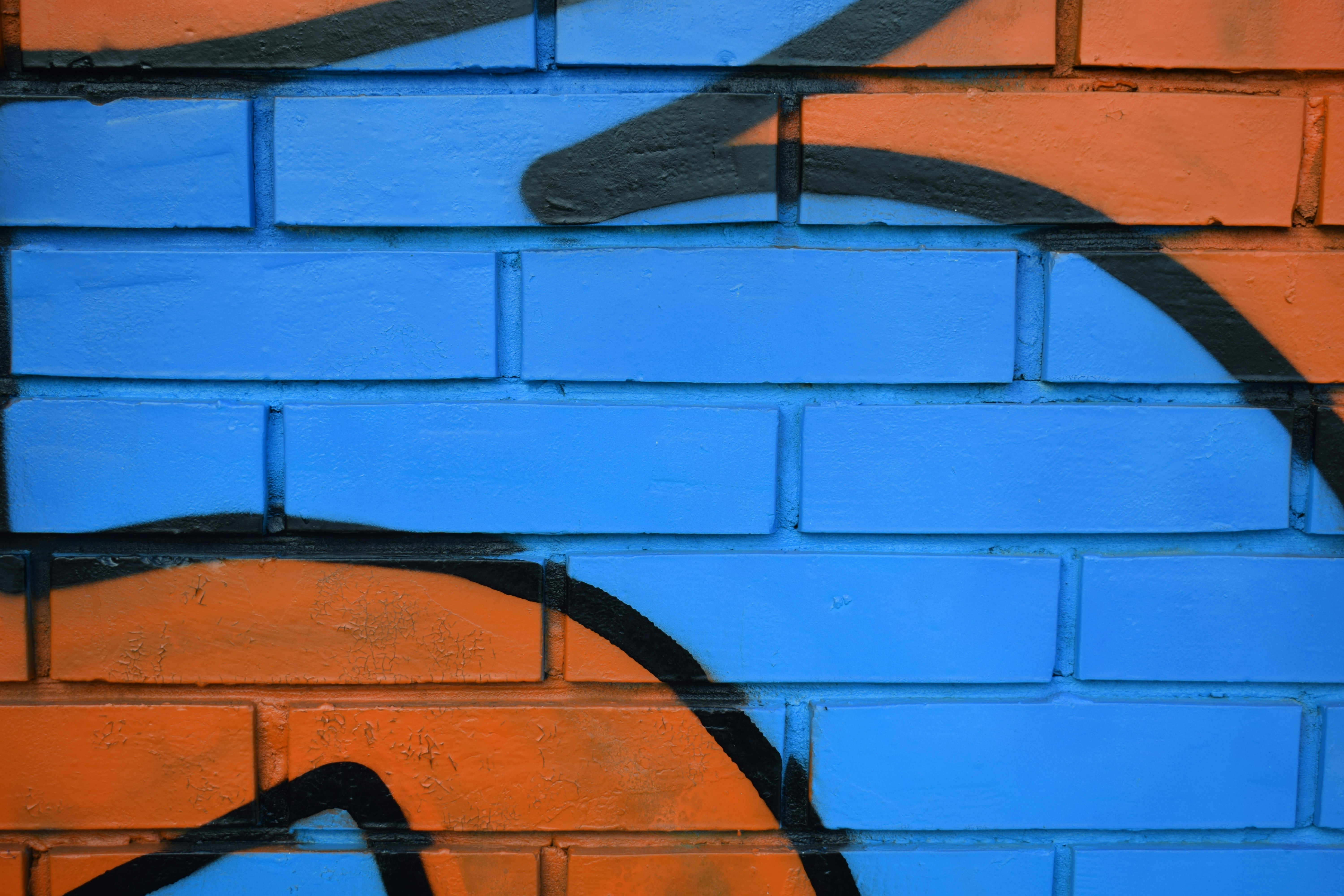 a blue and orange brick wall with graffiti on it