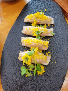 Artful plating of rainbow shrimp and chicken rolls with ginger and special sauces on a minimalist black surface