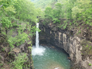 A vibrant waterfall cascading down rocky cliffs into a clear mountain pool.