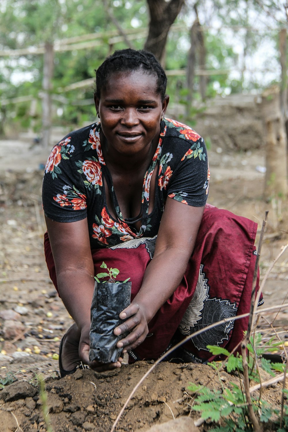 a woman kneeling down in the dirt with a glove