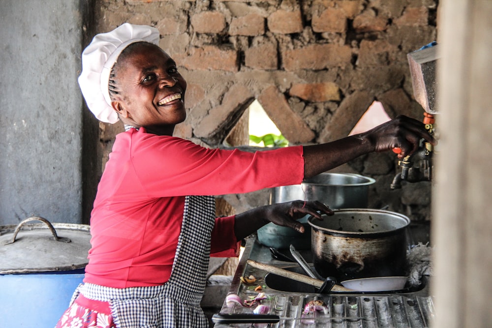 a woman in a red shirt is cooking in a kitchen