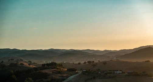 Sunset over rolling hills with rustic stone houses in Zocca, Emilia Apennines.