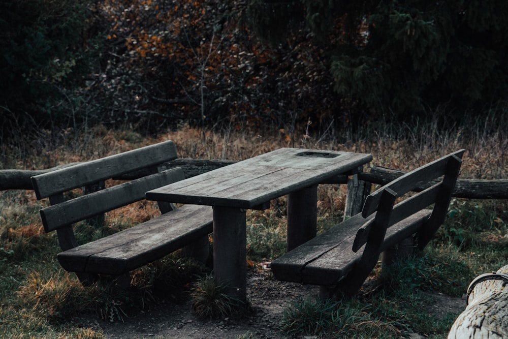 a wooden table and two benches in a field